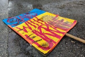 Schild "Stand with Ukraine" auf dem Boden, symbolisiert Unterstützung und aktuelle Hilfsproblematik.