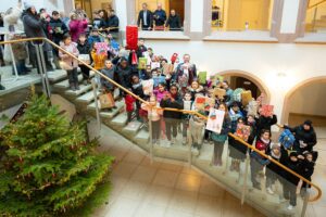 Kinder feiern die Geschenkübergabe der Wunschbaum-Aktion im festlich geschmückten Rathaus Ulm.