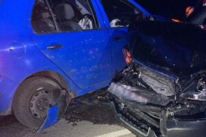 Zwei beschädigte Autos nach Unfall, Rettungsdienste, Verletzte werden versorgt, Verkehrsbehinderungen.