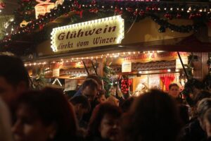Voller Glühweinstand auf Weihnachtsmarkt, Menschen genießen festliche Stimmung trotz geringer Besucherzahlen.