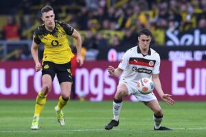Dortmund-Spieler jubeln nach dem Sieg gegen St. Pauli, Elfmeter sorgt für glücklichen Abschluss.