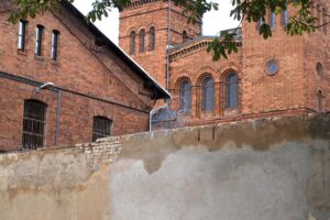 Ein Gefängnis mit Männern in Uniform und einem Wächter, symbolisch für Verhaftung und Justiz.