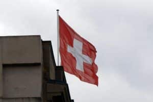 Schweizer Flagge vor einem Trauerszenario, symbolisiert das Unglück in Crans-Montana.