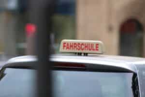 Fahrschule mit Schülern, Fahrlehrer, Auto, und Materialien für Theorie- und Praxisunterricht.