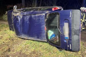 Unfallwagen auf Seite liegend, Polizei vor Ort, Unfallstelle auf ländlicher Straße.