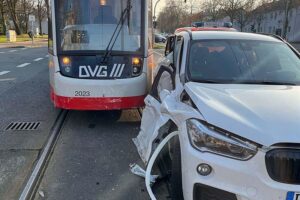 Unfallstelle mit beschädigtem BMW, Straßenbahn und Rettungskräften in Duisburg-Aldenrade.