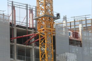 Baustelle mit Bauarbeiten, Materialien und Handwerkern, die steigende Baupreise illustrieren.