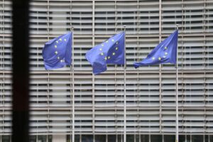 EU-Fahnen im Vordergrund, symbolisieren regulatorische Maßnahmen gegen Elon Musks KI-Chatbot Grok.
