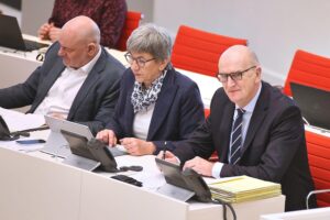 Drei Politiker diskutieren ernsthaft über Regierungskoalitionen und politische Entscheidungen in Brandenburg.