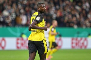 Ein Fußballfeld mit jubelnden Dortmund-Spielern, Toren und Fans im Stadion.
