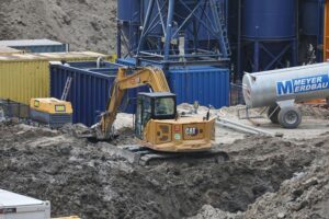 Baustelle mit Bauarbeitern und neuen Wohngebäuden, Symbol für Wohnungsbau und Baugenehmigungen.