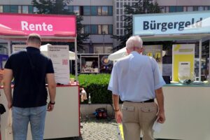 Passanten informieren sich an Infoständen über Rente und Bürgergeld in Hamburg.