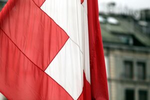 Schweizer Fahne über dem Skiort Crans-Montana, während Notfallkräfte nach Explosion arbeiten.