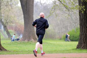 Jogger im Freien, umgeben von Natur, symbolisiert sportliche Aktivität und Fitnessbewusstsein in Deutschland.