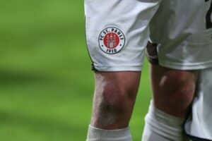 Mathias Rasmussen in FC St. Pauli-Trikot, jubelnd mit Teamkollegen auf dem Spielfeld.