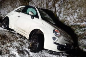 Verunfalltes Fahrzeug im Straßengraben, Feuerwehr und Rettungsdienst vor Ort, Unfallstelle gesichert.