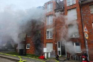 Feuerwehr rettet Bewohner aus brennendem Keller; starkes Rauchaufkommen, Einsatz von Drehleitern sichtbar.