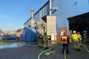 Feuerwehr löscht Brand in Gewerbebetrieb; Flammen aus Absauganlage, schnelle Einsatzkräfte im Einsatz.