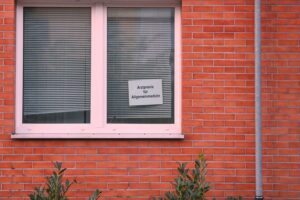 Arztpraxis mit wartenden Patienten, während Gesundheitsreformen und Beitragserhöhungen diskutiert werden.