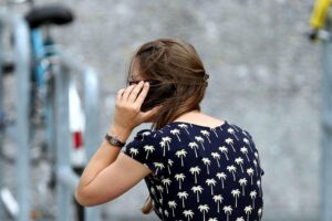 Junge Frau vergleicht Smartphone-Preise, zeigt Einsparpotenziale beim getrennten Kauf von Tarifen.