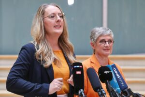 Zwei grüne Politikerinnen diskutieren kritische Handelsabkommen in unsicherer geopolitischer Lage.