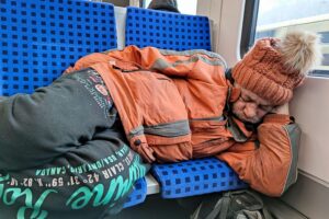 Obdachloser schläft im Zug während starkem Schneefall in Hamburg. Hilfe und Schutz bieten.