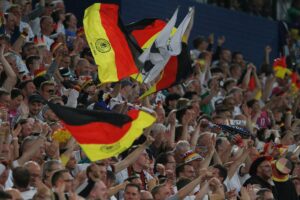Deutsche Fußballfans feiern gemeinsam, umgeben von Nationalflaggen, im Vorfeld der WM 2026.