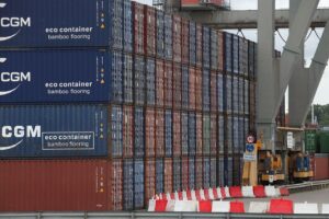 Container im Hafen mit Preistafel, symbolisiert sinkende Importpreise und Energiepreise.