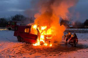 Feuerwehrlöscharbeiten an einem komplett ausgebrannten Auto auf einem Feld in Weinheim.