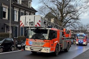 Feuerwehr löscht Küchenbrand, Rauchbildung und Einsatzkräfte am Mehrfamilienhaus in Remscheid sichtbar.