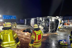 Umgekippter Kühllaster auf Autobahn mit Feuerwehr und Einsatzkräften am Unfallort.