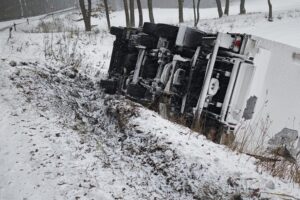 Lastwagenunfall auf winterglatter Straße; Fahrzeug im Graben, Polizei und Feuerwehr im Einsatz.