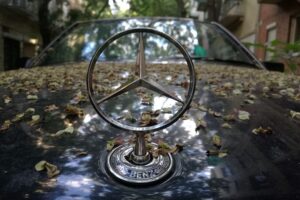 Mercedes-Stern vor Hintergrund futuristischer Autos, Symbol für autonome Fahrtechnologie und strategische Neuausrichtung.
