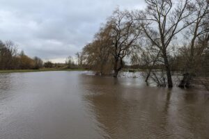 Bild zeigt Hochwasser, zerstörte Landschaft und Menschen, die von Naturkatastrophen betroffen sind.