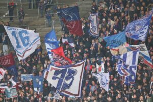 Kiel-Fans jubeln im Stadion, während Polizei präventiv gegen Gewalttäter vorgeht.