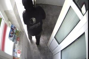 Fahndungsbild eines Verdächtigen nach Raub und Betrug, gesicht verdeckt, auffällige Jacke.