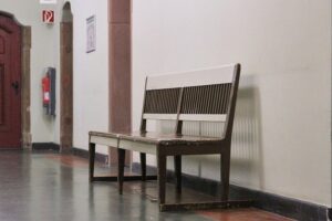 Sitzbank im Gericht, symbolisiert Personalengpass und Digitalisierungsprobleme der Justiz.