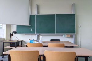Ein leerer Klassenraum mit Tischen, Stühlen und einer Tafel für individuellen Unterricht.