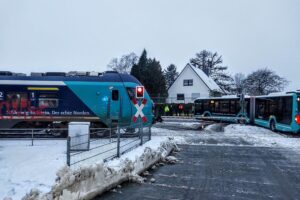 Ein Schulbus steckt auf einem Bahnübergang fest, während Kinder sicher evakuiert werden.