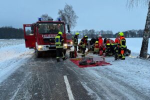 Unfallstelle mit umgekipptem Auto, Feuerwehr und Rettungsdienst bei der Bergung der Fahrerin.