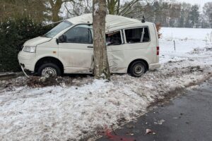 Schwerer Unfall: VW-Bus prallt gegen Baum auf winterglatter Straße, Fahrer verletzt.