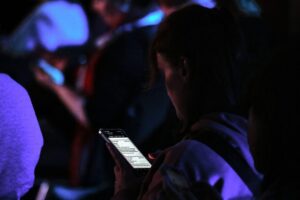Junge Frau legt Smartphone weg und genießt eine kurze digitale Auszeit für bessere Stimmung.