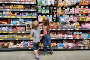 Kinder wählen Süßigkeiten im Supermarkt, während die Süßwarenproduktion in NRW sinkt.