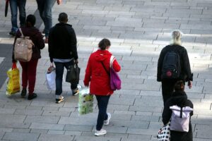 Buntes Treiben in einer belebten Fußgängerzone, Menschen fröhlich beim Einkaufen und Verweilen.