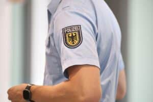 Bundespolizisten am Hamburger Flughafen überwachen Reisende, Haftbefahl wird überprüft.