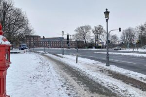 Schneebedeckte Straße in Berlin mit Warnhinweis zu Glatteis und gefährlichen Bedingungen.