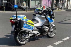 Polizeimotorrad am Unfallort zwischen Motorrad und Rollstuhl, schwer verletzte Personen.