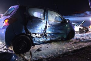Zwei beschädigte Autos nach Verkehrsunfall, Polizisten sichern Unfallstelle, Verletzte werden versorgt.