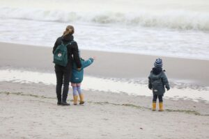 Eltern mit Hochschulabschluss verbringen mehr Zeit mit ihren Kindern am Strand beim Spielen.