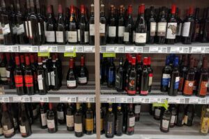 Rotweinflasche auf Holztisch, Symbol für Alkohol und dessen Auswirkungen auf die Gesundheit.